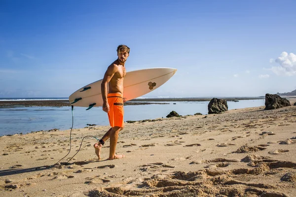 Sportlicher junger Sportler mit Surfbrett am Sandstrand — Stockfoto