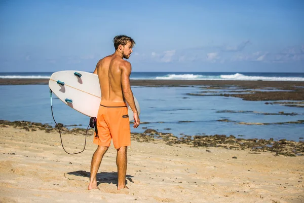 Jovem com prancha de surf na praia perto do oceano — Fotografia de Stock