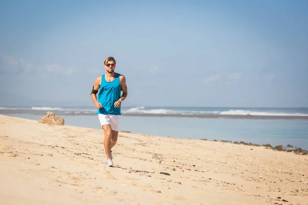 Apuesto deportista corriendo en la orilla del mar - foto de stock