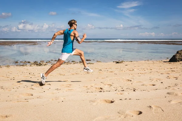 Homme athlétique courir et sauter sur la plage de sable près de la mer, Bali, Indonésie — Photo de stock