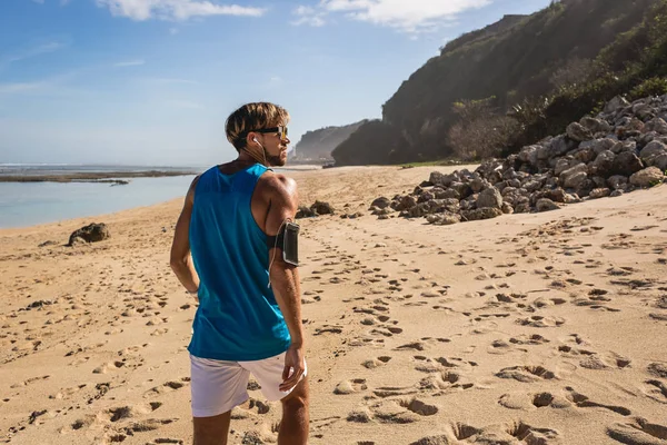 Vista trasera del hombre guapo caminando en la orilla del mar, Bali, Indonesia - foto de stock