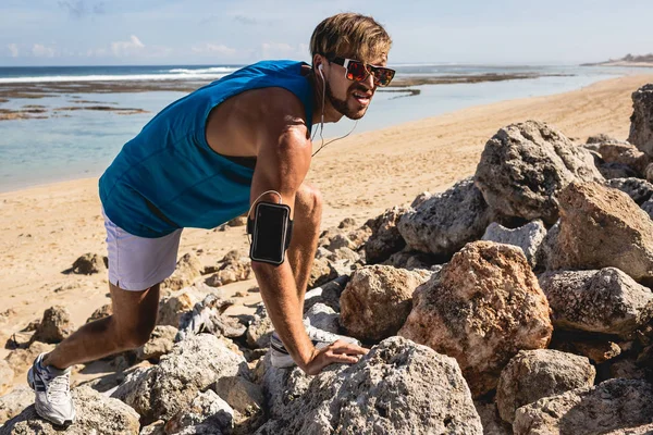 Uomo atletico con bracciale arrampicata su rocce sulla spiaggia, Bali, Indonesia — Foto stock