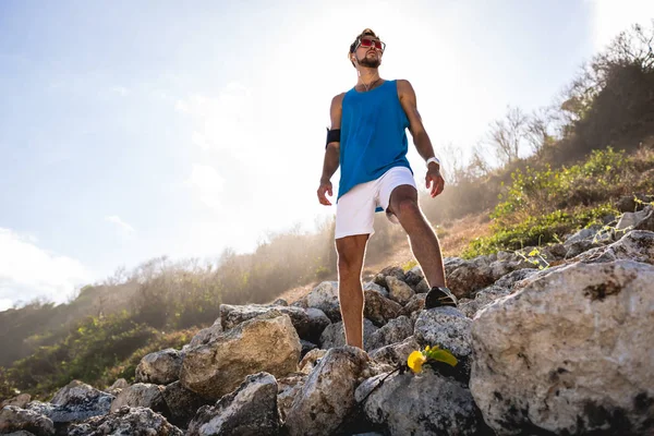 Вид снизу спортсмена, стоящего на скалах с солнечным светом — стоковое фото