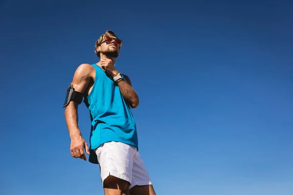 Vue du bas du sportif en lunettes de soleil avec brassard smartphone — Photo de stock