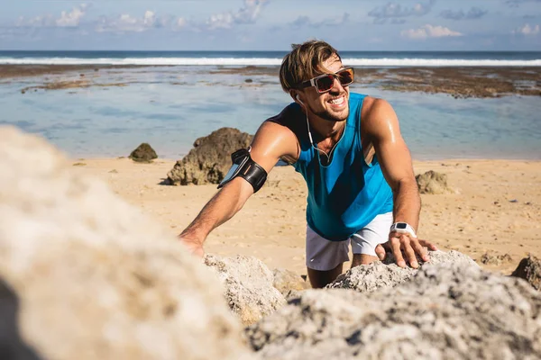 Smiling sportsman climbing on rocks on beach, Bali, Indonesia — Stock Photo