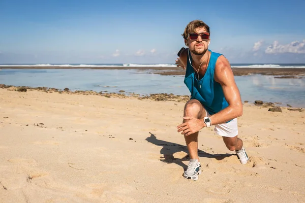 Спортсмен делает выпады во время тренировки на пляже у моря — стоковое фото