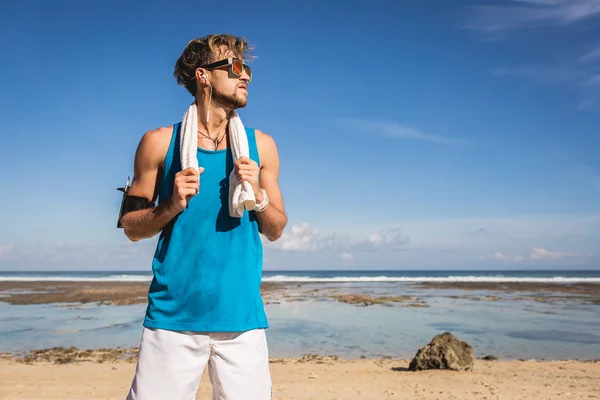 Desportista bonito com toalha de pé na praia — Fotografia de Stock