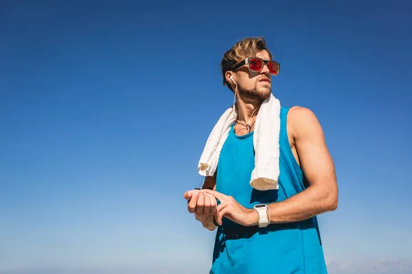Sportsman in sunglasses with towel counting pulse on wrist — Stock Photo