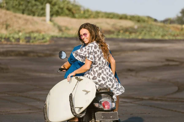 Back view of couple riding scooter with surfboard on beach in bali, indonesia — Stock Photo