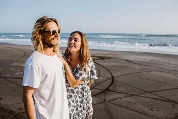 Pareja sonriente abrazándose en la costa en bali, indonesia - foto de stock