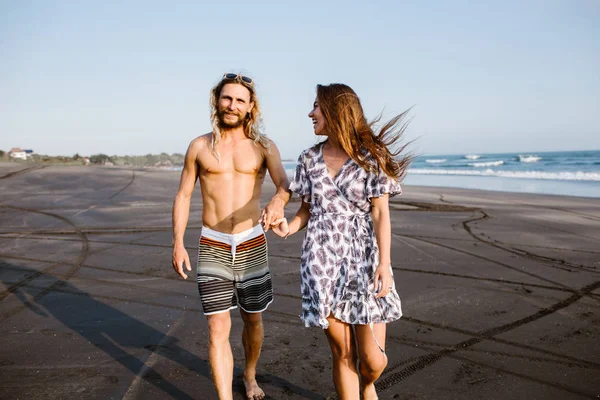 Smiling couple holding hands and walking on beach in bali, indonesia — Stock Photo
