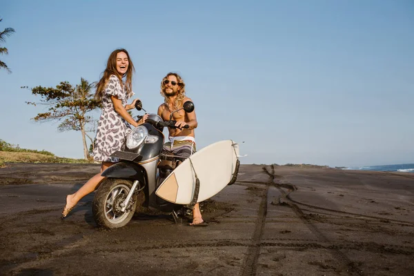 Couple riant avec scooter et planche de surf sur la plage à Bali, indonesia — Photo de stock