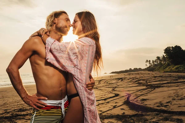 Couple hétérosexuel câlins sur la plage pendant le coucher du soleil à bali, indonesia — Photo de stock