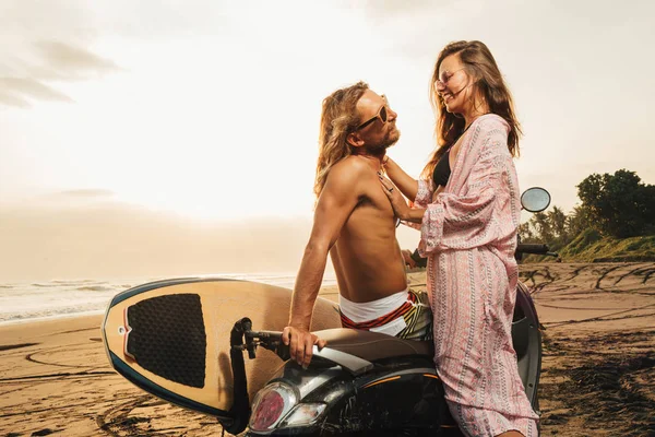 Smiling couple hugging near scooter on beach during sunset in bali, indonesia — Stock Photo