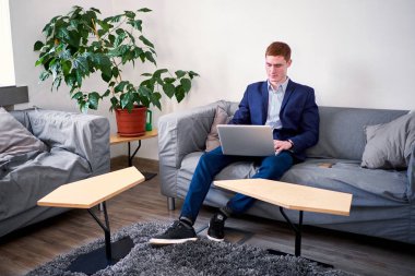 Olgun Avrupa adam kanepede dizüstü bilgisayar kullanarak