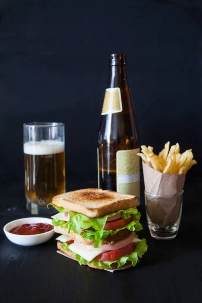 Sándwich con cerveza y papas fritas sobre fondo negro — Foto de Stock