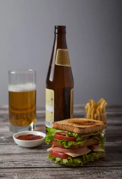 Sándwich con cerveza, salsa, papas fritas en una mesa de madera. Hor. — Foto de Stock