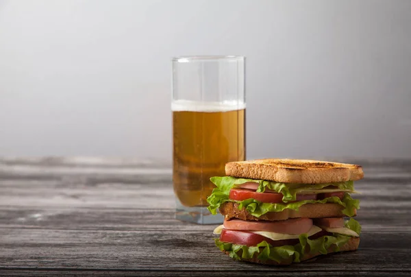 Sandviç ve bir bardak bira ahşap bir masa üzerinde — Stok fotoğraf