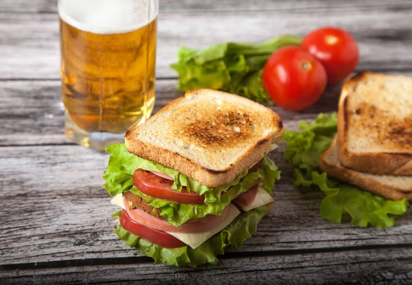 Sanduíche, tomate, torrada, salada e vidro com cerveja em um em um woo — Fotografia de Stock