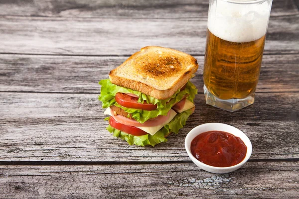 Sándwich con cerveza, y salsa en una mesa de madera — Foto de Stock