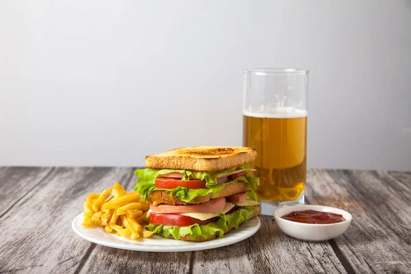 Sanduíche e batatas fritas em um prato com molho e suporte de cerveja — Fotografia de Stock
