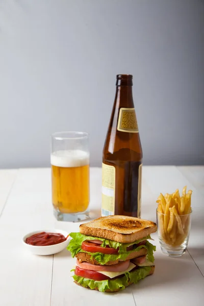 Sándwich, una botella de cerveza, papas fritas, salsa en un woo blanco — Foto de Stock