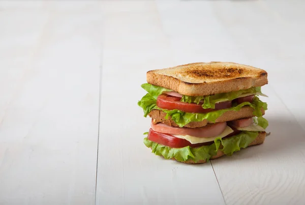 Sandviç et ve peynir ile bir beyaz tahta masada yatıyor — Stok fotoğraf