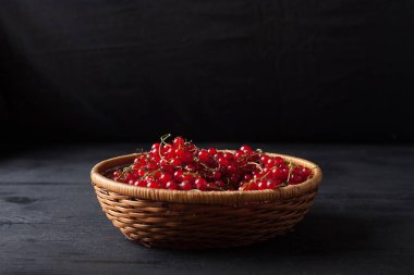 siyah bir zemin üzerine bir sepet içinde kırmızı kuş üzümü