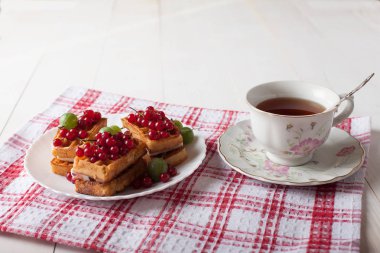 Kuş üzümü ve bir fincan çay ile Viyana waffle masada damalı bir masa örtüsü üzerinde durmak