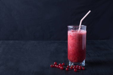 bir bardak taze smoothies siyah bir masada duruyor