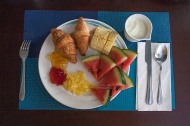 Otelde kahvaltı. Kruvasan ile reçel, yoğurt ve meyve beyaz bir plaka üzerinde