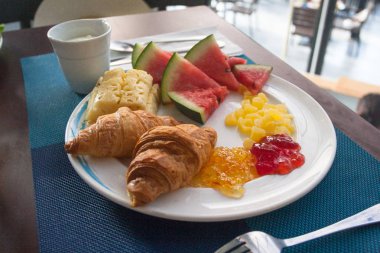 Otelde kahvaltı. Kruvasan ile reçel, yoğurt ve meyve beyaz bir plaka üzerinde