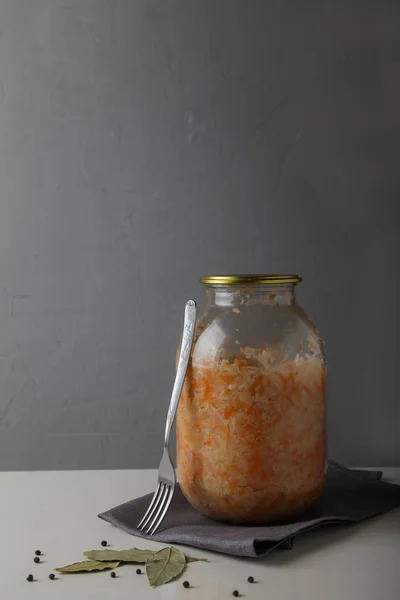 Sauerkraut в скляній банці з кришкою і виделкою стоїть на білому — стокове фото