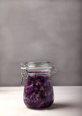 gri arka planda kapağı olan cam bir kavanozda fermente lahana