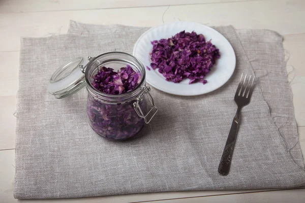 Fermentierter Rotkohl in Gläsern, ein Teller mit Salatständer auf einem Tisch — Stockfoto