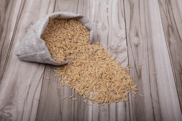 cilasız pirinç ahşap bir arka plan üzerinde bir çanta dağınık