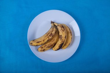 çirkin muz mavi bir arka plan üzerinde mavi bir porselen plaka üzerinde yalan