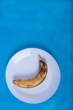çirkin muz mavi bir arka plan üzerinde mavi bir porselen plaka üzerinde yalan. 