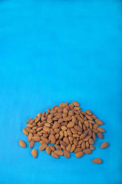 Almonds on a blue background. Flat jay. Copy spais. Vertical. — Stock Photo, Image