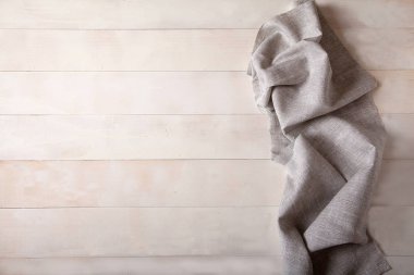 Beyaz ahşap arka plan üzerinde gri keten peçete. Düz yatıyordu.