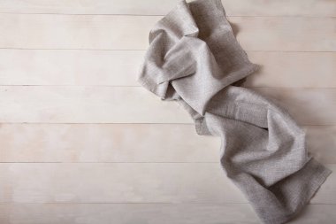 Keten gri havlu beyaz ahşap bir arka plan üzerinde yatıyor. Düz yatıyordu. Kopya cpaes.