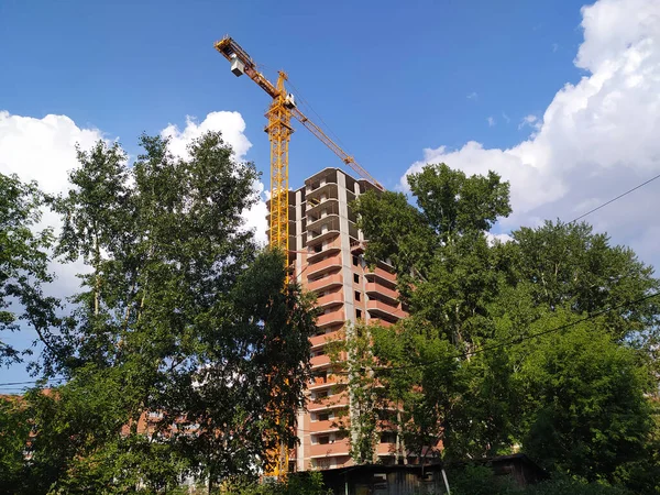 高い建設クレーンは 青い空と雲に対して緑の森の中に新しい家を構築しています 生態学 環境だ 携帯写真 — ストック写真