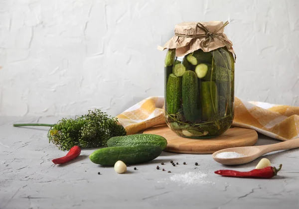 Mayalanmış salatalıklı büyük kavanoz, tahta kaşıkta tuz ve çimento arka planda baharatlar. Kürekleri kopyala. yatay