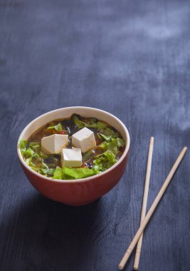 Tofu peyniri ve sebzeli Japon çorbası, siyah arka planda çubuklar. Kürekleri kopyala