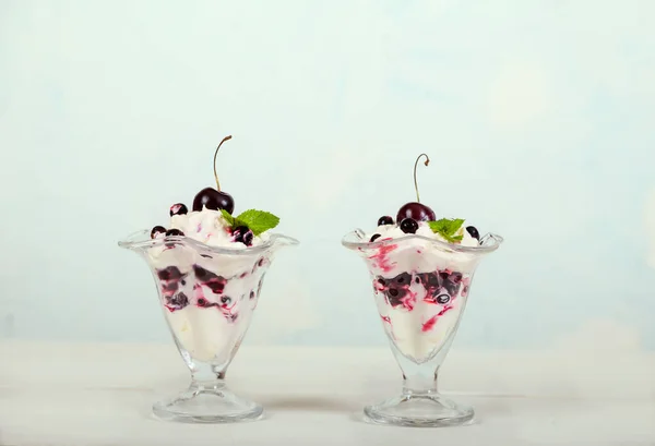 Whipped cream dessert with cherries and currants, garnished with mint leaves on a light blue background. Healthy eating. Organic products