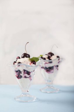 Krema, üzümlü ve kirazlı, beyaz tabakta nane yapraklarıyla süslenmiş. Kürekleri kopyala. dikey.