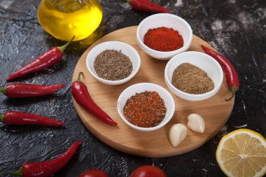 Harissa için yer baharatları, domates, limon, siyah arka plandaki ahşap tezgahta yağ..