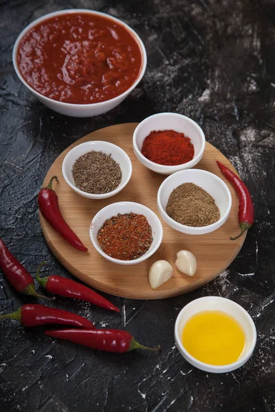 Harissa, baharat kimyonları, beyaz porselen bardaklarda biberler, sarımsak ve acı biber biberleri ve sebze yağı standı..