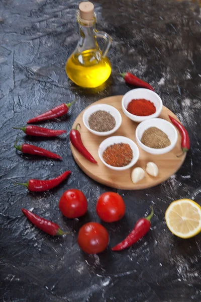 Harissa için yer baharatları, domates, limon, siyah arka plandaki ahşap tezgahta duran yağ. dikey.