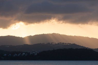 Koh Samui, Tayland, gün batımı sırasında altın sunburst gölet aşağı dağ aracılığıyla bulutlar deniz yansıtan ışık parlar.